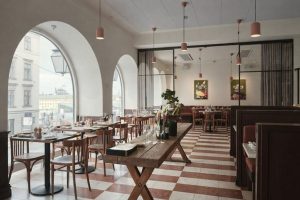 Ljust restauranginteriör med rutigt golv och fönster med utsikt över staden på Södermalm.